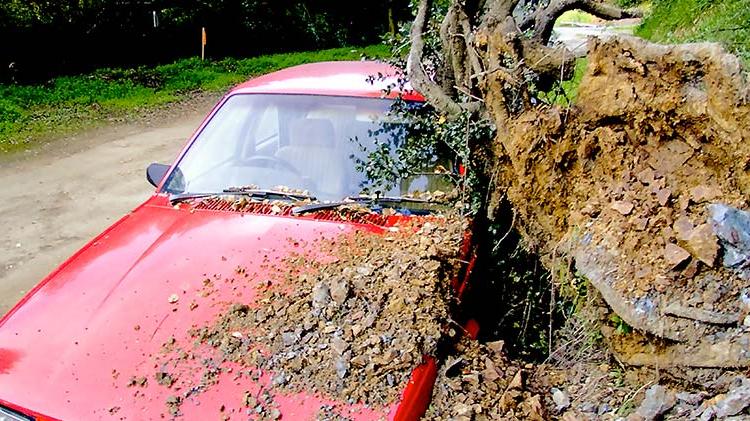 Red car covered with debris from a landslide.