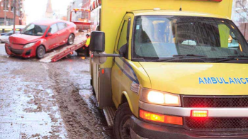 一辆黄色救护车停在一辆受损的白色车辆附近.